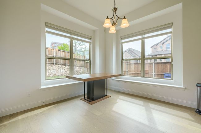 Unfurnished dining area featuring baseboards, a chandelier, light wood-type flooring, and plenty of natural light | Image 14