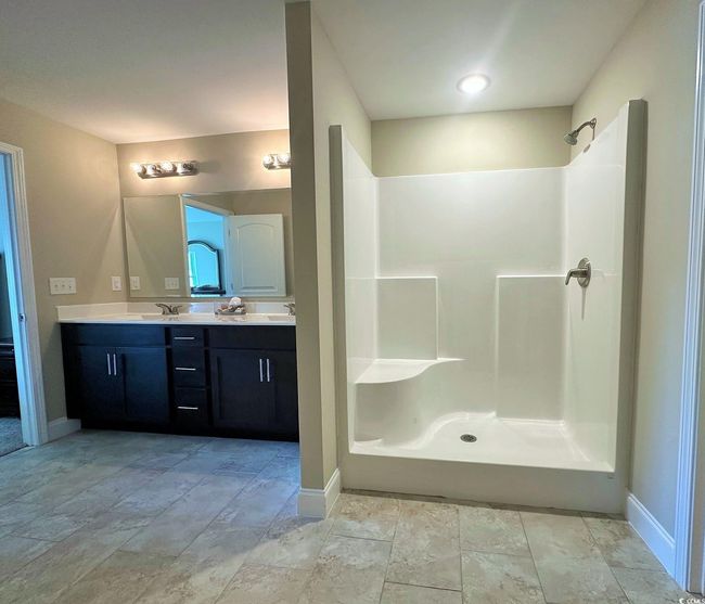 Bathroom featuring baseboards, a sink, a shower, stone finish floor, and double vanity | Image 9