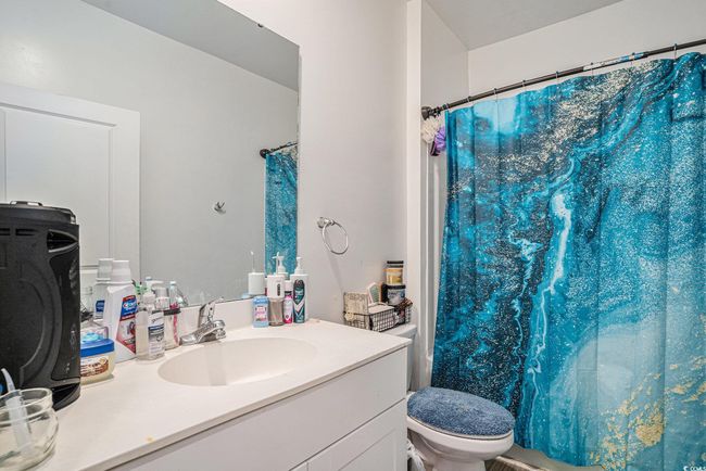 Bathroom with toilet, vanity, and a shower with shower curtain | Image 23