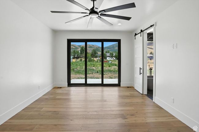 Spare room featuring a barn door, a mountain view, light wood-type flooring, a ceiling fan, and recessed lighting | Image 28