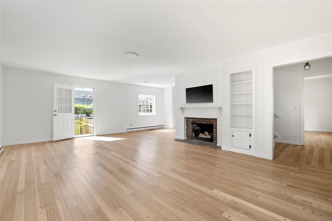 Unfurnished living room with light wood finished floors, a baseboard radiator, baseboards, and built in features | Image 11