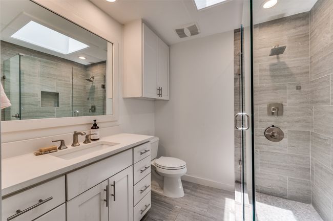 Full bath featuring a skylight, a shower stall, vanity, toilet, and recessed lighting | Image 21