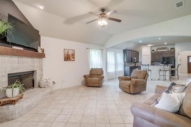 Living area with vaulted ceiling, arched walkways, ceiling fan, a brick fireplace, and light tile patterned floors | Image 18