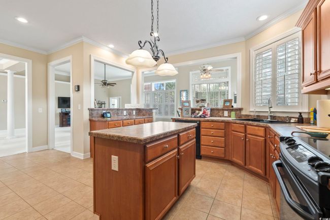 Kitchen featuring light tile patterned floors, a sink, a kitchen island, black appliances, and a ceiling fan | Image 7