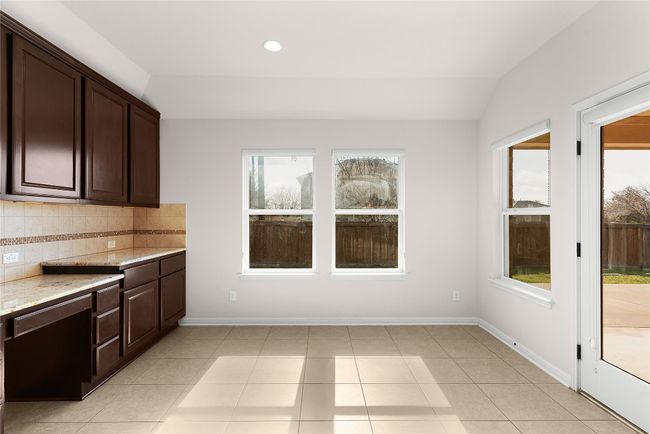 Kitchen with decorative backsplash, dark brown cabinetry, and a wealth of natural light | Image 29