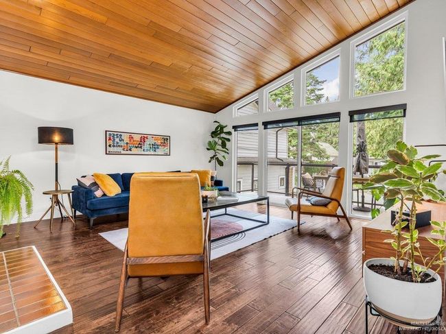 Spacious open concept living Room with vaulted warm wood ceiling, full height west facing (new) windows flooding the room with natural light, and a cozy gas fireplace as a central focal point in the 'Great Room'. | Image 8