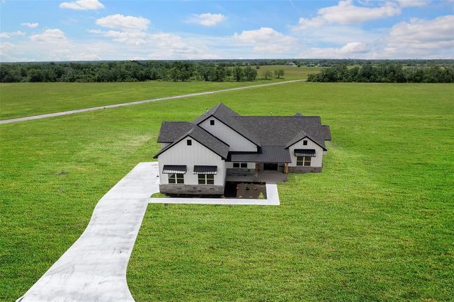 Stunning aerial view showcasing a modern farmhouse with a spacious front yard and beautiful countryside surroundings. Perfect for those seeking tranquility and style. | Image 48