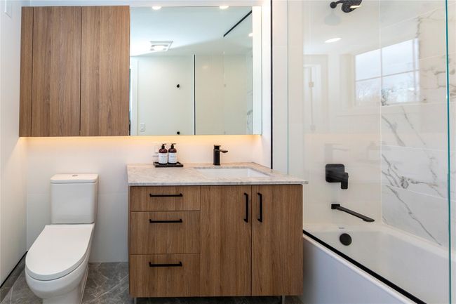 Showcasing beautiful tile work, soft-closing vanities with natural stone tops, under-cabinet lighting, and a tub. | Image 26