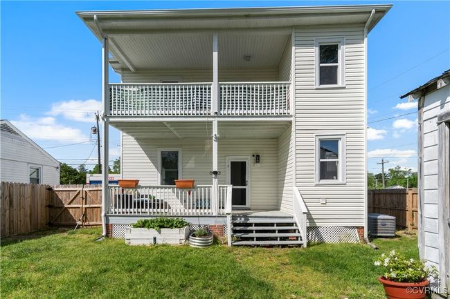 Rear view of house featuring a fenced backyard, central AC, a balcony, and a lawn | Image 38
