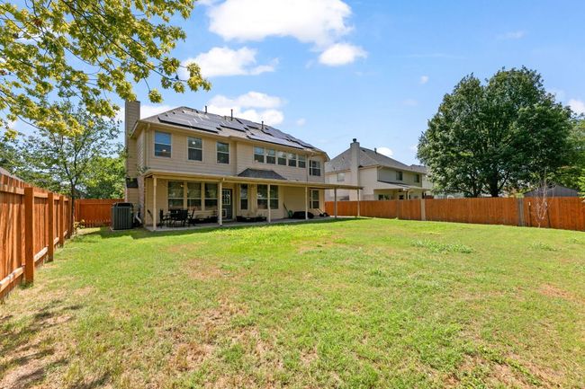 Back of house with roof mounted solar panels, a fenced backyard, a chimney, and a patio | Image 28