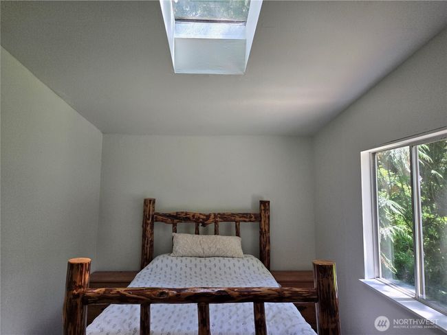 Primary bedroom has skylight for additional lighting. The room is large enough to easily accommodate this queen size bed with end tables. | Image 15