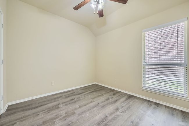 Empty room with a ceiling fan, healthy amount of natural light, light wood-style floors, and vaulted ceiling | Image 22