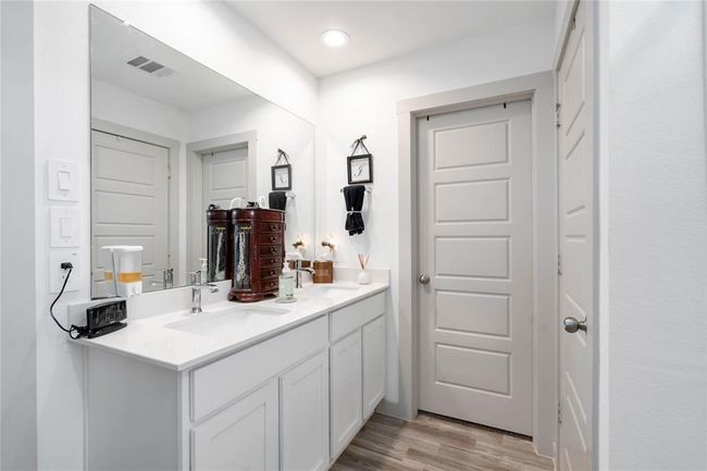Spacious primary bathroom featuring dual sinks, sleek quartz countertops, and ample storage with white cabinetry. | Image 10
