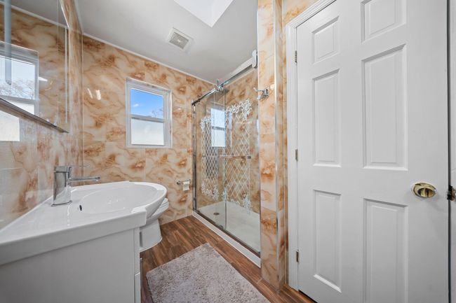 Full bath featuring vanity, wood finished floors, visible vents, a stall shower, and tile walls | Image 12