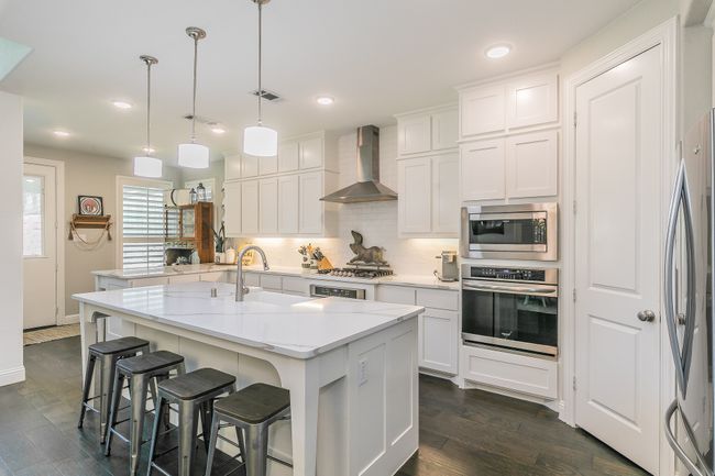 Kitchen with appliances with stainless steel finishes, tasteful backsplash, a breakfast bar, white cabinets, and recessed lighting | Image 8
