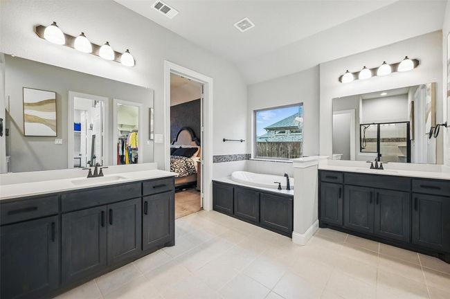 Bathroom with a garden tub, two vanities, tile patterned flooring, vaulted ceiling, and a shower stall | Image 25