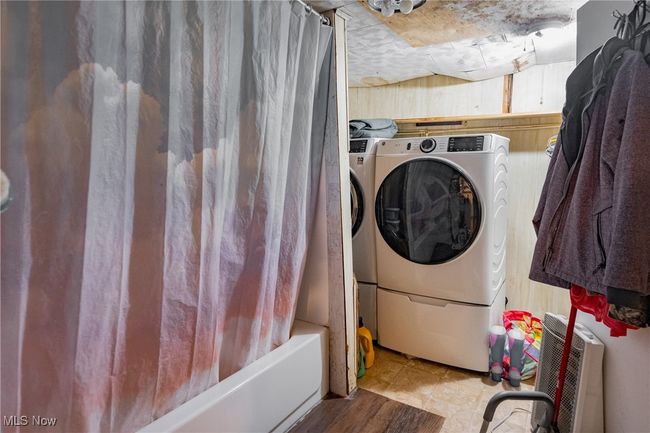 Laundry area featuring washing machine and clothes dryer and wood walls | Image 12