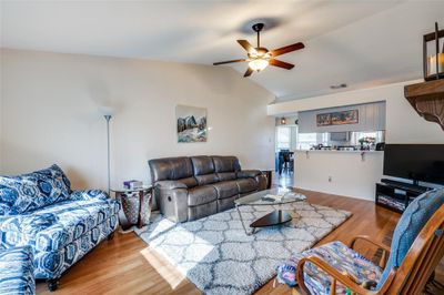 Living room with wood-type flooring, vaulted ceiling, and ceiling fan | Image 3