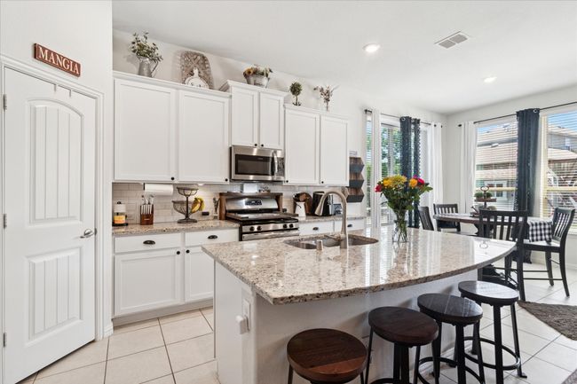 Chef’s island kitchen with stunning granite countertops, a stylish subway tile backsplash, and premium stainless-steel appliances. | Image 11