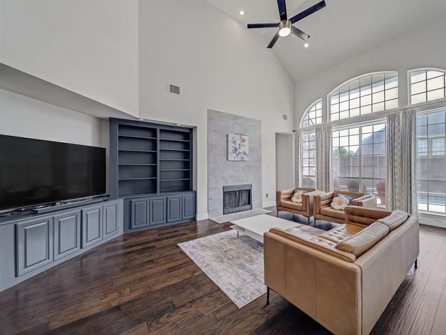 Living room featuring high vaulted ceiling, dark wood finished floors, a ceiling fan, healthy amount of natural light, and a tile fireplace | Image 5