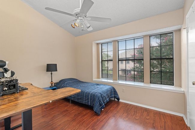 Bedroom featuring multiple windows, vaulted ceiling, wood finished floors, ceiling fan, and a textured ceiling | Image 12