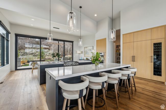 Kitchen with a center island, a healthy amount of sunlight, light wood-style floors, a high ceiling, and light countertops | Image 26