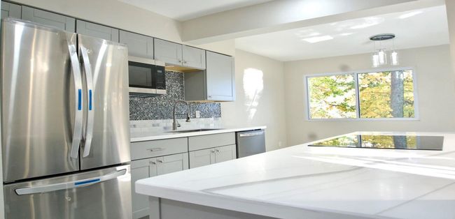 Kitchen with light stone countertops, a sink, stainless steel appliances, decorative backsplash, and gray cabinetry | Image 17