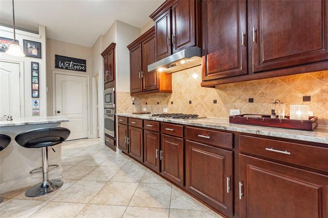 Ample wood cabinet storage and attractive backsplash. | Image 25