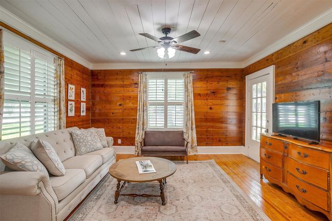 Living room featuring ceiling fan, wooden walls, crown molding, light wood finished floors, and wooden ceiling | Image 14
