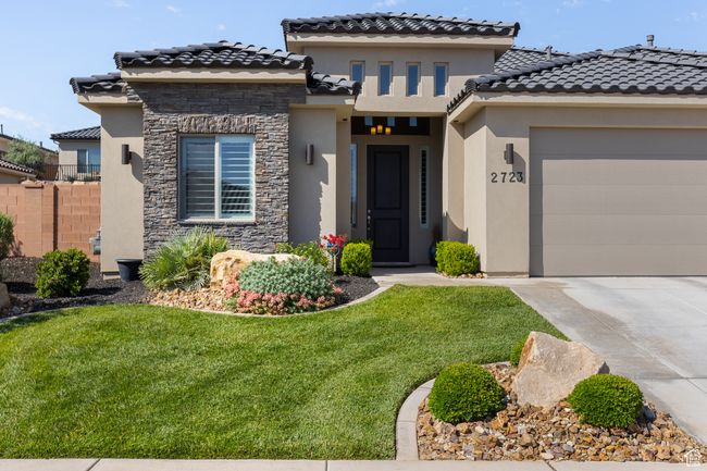 Mediterranean / spanish-style home featuring stucco siding, concrete driveway, stone siding, an attached garage, and a tiled roof | Image 59