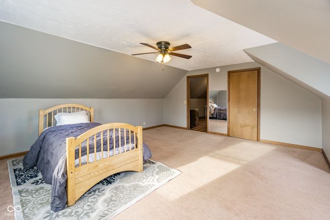 carpeted bedroom featuring baseboards, multiple closets, vaulted ceiling, and a ceiling fan | Image 23