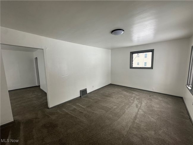 Empty room with baseboards, dark colored carpet, and visible vents | Image 22