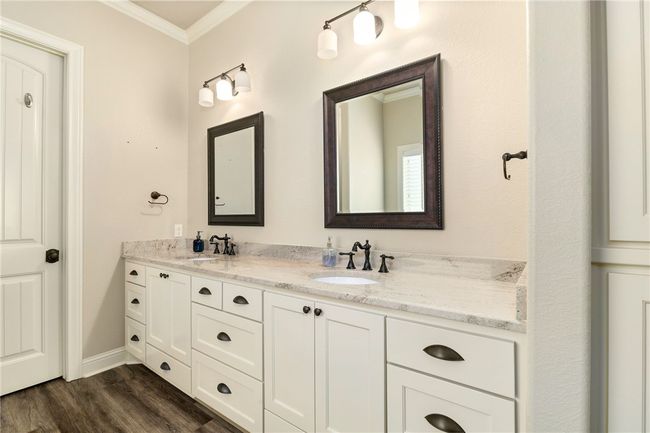 Step into your ensuite bathroom, featuring a spacious granite-topped vanity with dual sinks, framed mirrors, abundant lighting, and stylish bronze finishes. | Image 19