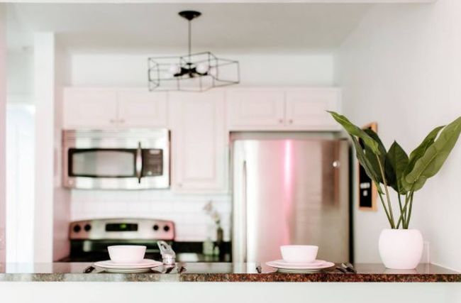 Kitchen featuring stainless steel microwave, freestanding refrigerator, range, white cabinets, and backsplash | Image 9