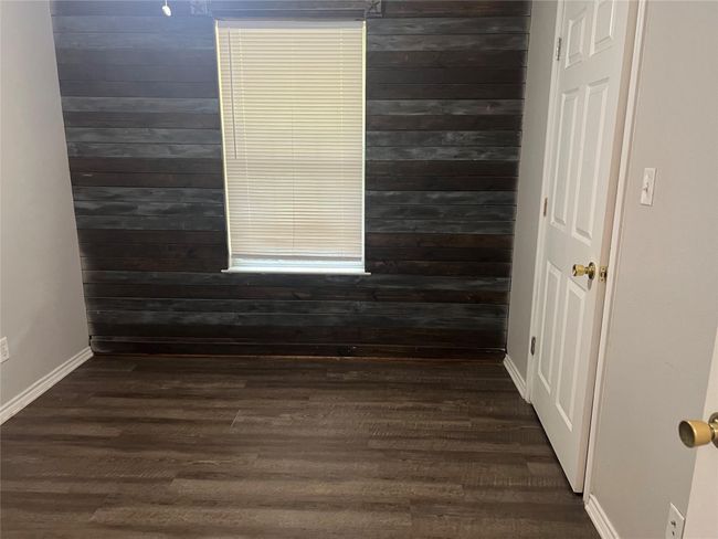 Spare room with dark wood-style flooring and wood walls | Image 7