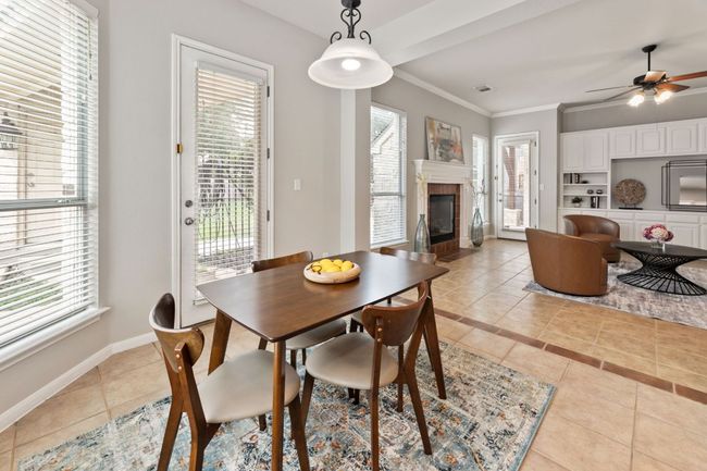 Dining room with light tile patterned floors, a tiled fireplace, healthy amount of natural light, and crown molding | Image 15