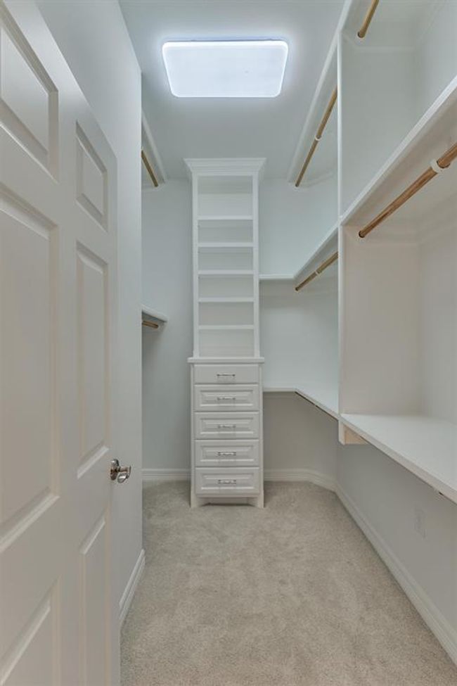One of the two primary closets features built-in shelving and drawers and abundant hanging space, offering both organization and functionality. | Image 26
