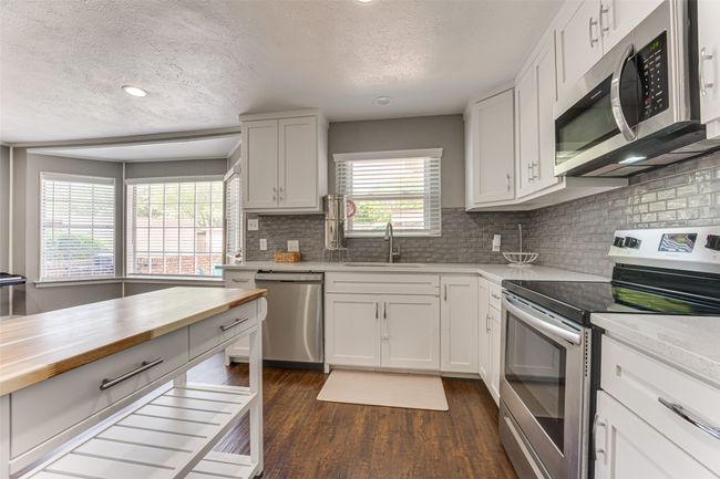 Kitchen with a textured ceiling, appliances with stainless steel finishes, a sink, and wooden counters | Image 11
