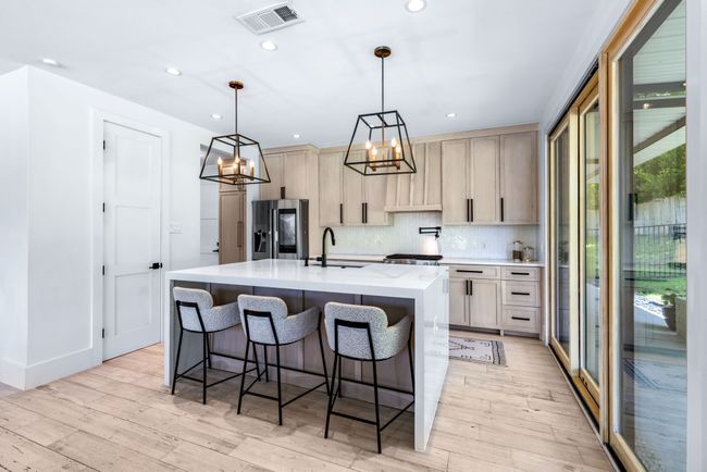 Kitchen featuring stainless steel refrigerator with ice dispenser, light wood-type flooring, a chandelier, decorative backsplash, and recessed lighting | Image 14