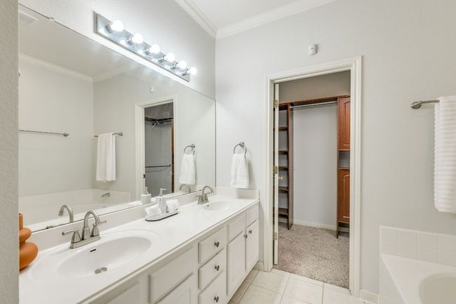 Bathroom with tile patterned floors, a bath, crown molding, double vanity, and a walk in closet | Image 20