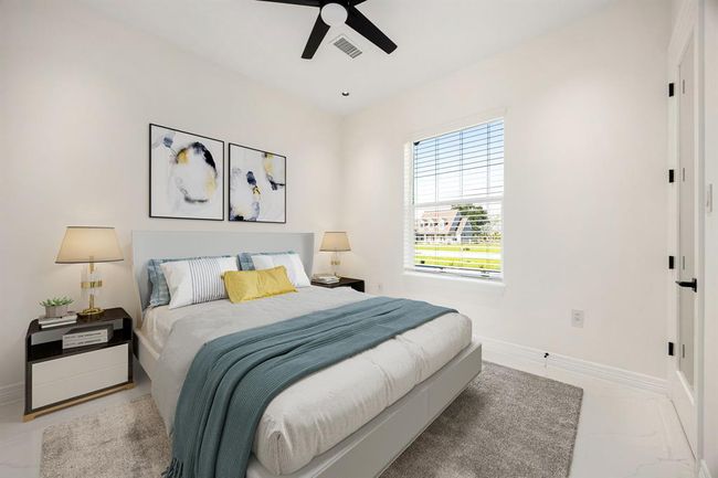 This bright and inviting secondary bedroom features a large window that fills the space with natural light, complemented by a soothing neutral palette and modern finishes. A ceiling fan, plush carpeting, and tasteful decor make this room both comfortable and stylish—perfect for guests or family. | Image 33