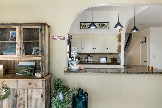 Kitchen featuring arched walkways, backsplash, white cabinets, and pendant lighting | Image 18