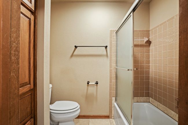 Full bath featuring enclosed tub / shower combo and tile patterned flooring | Image 25