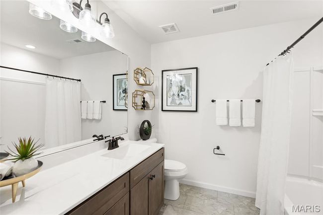 Bathroom featuring toilet, vanity, marble look tile flooring, baseboards, and shower / bath combo | Image 21