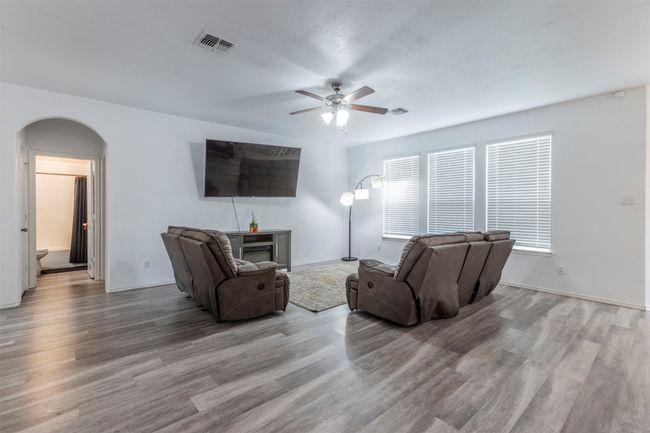 Living area with visible vents, wood finished floors, a fireplace, ceiling fan, and arched walkways | Image 4
