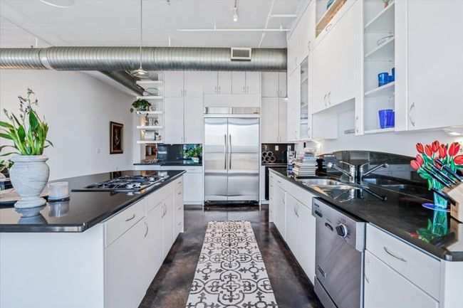 Kitchen featuring concrete floors, open shelves, Ink granite countertops, and stainless steel appliances | Image 7