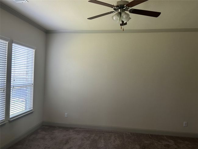 Empty room featuring dark carpet, ceiling fan, ornamental molding, and baseboards | Image 8