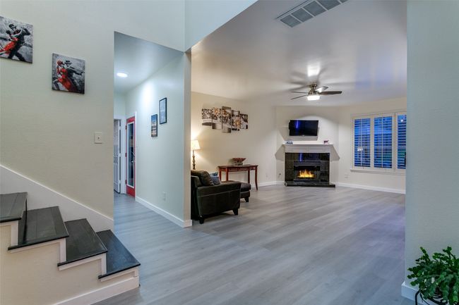 Living room featuring ceiling fan, wood finished floors, baseboards, and a lit fireplace | Image 7