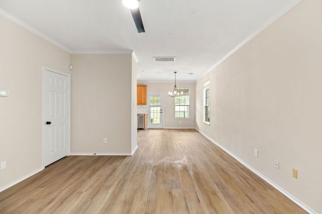 Spare room featuring light wood-type flooring, an inviting chandelier, baseboards, ornamental molding, and visible vents | Image 11