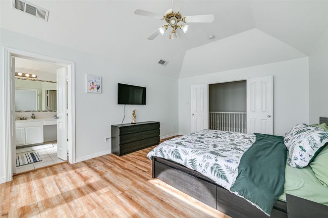 Bedroom featuring light wood-type flooring, ensuite bathroom, ceiling fan, and vaulted ceiling | Image 30